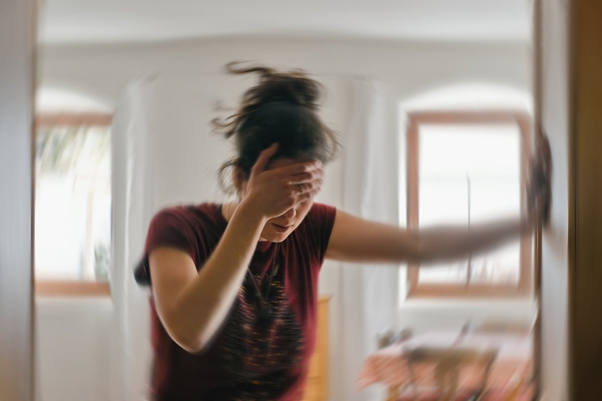 Woman suffering from vertigo and dizziness, holding her head due to a spinning sensation and inner ear balance disorder